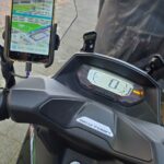 Zicht vanaf het stuur van een scooter met een digitaal dashboard en een gemonteerde smartphone met een navigatie-app