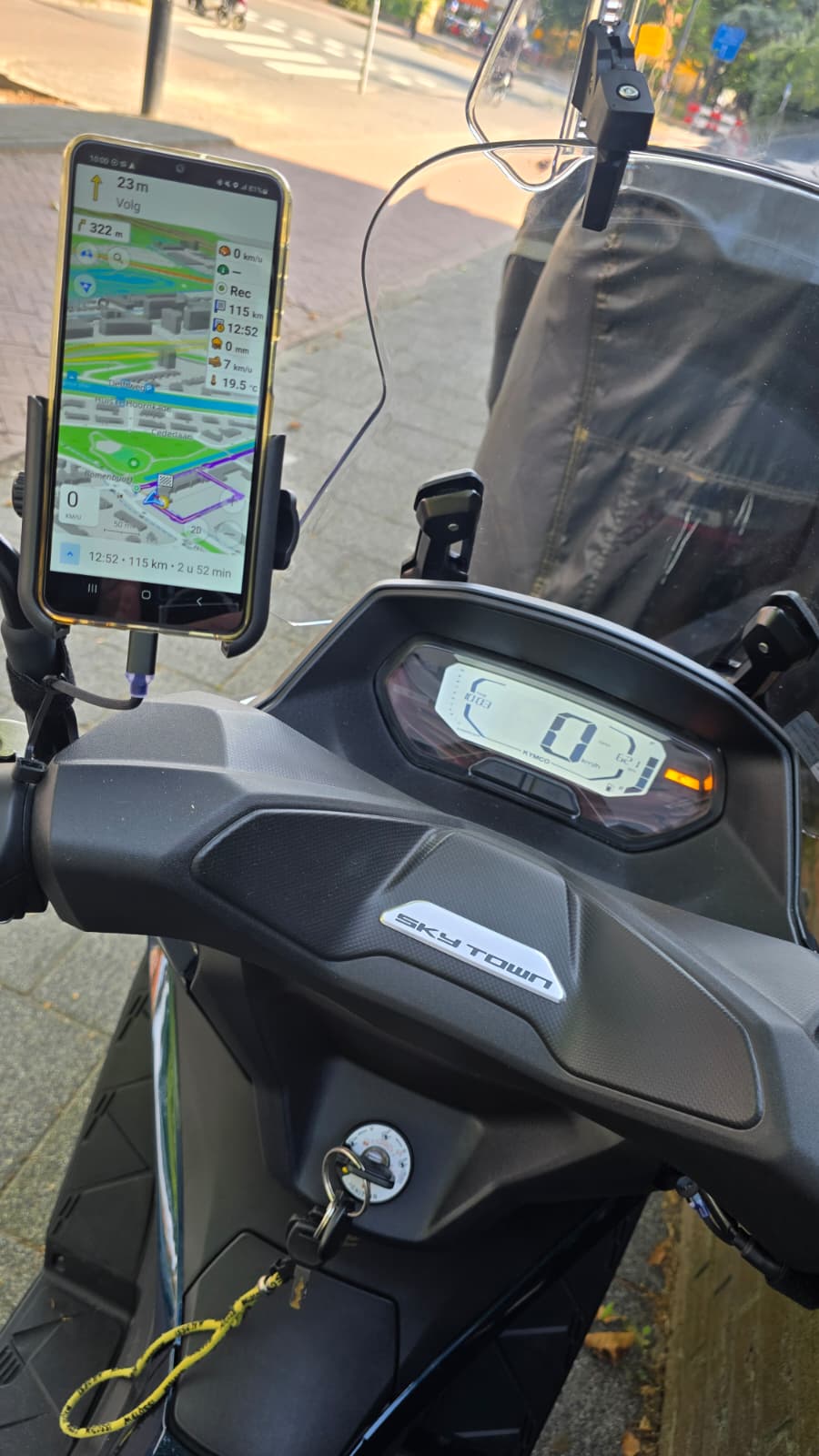 Zicht vanaf het stuur van een scooter met een digitaal dashboard en een gemonteerde smartphone met een navigatie-app