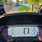Digitaal dashboard van een Kymco-scooter met een kilometerstand van 1000 km en een snelheid van 0 km/h