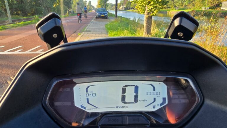 Digitaal dashboard van een Kymco-scooter met een kilometerstand van 1000 km en een snelheid van 0 km/h
